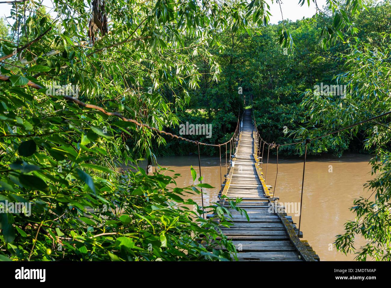 Pont suspendu en bois de l'autre côté de la rivière. Pont suspendu dans un petit village. Banque D'Images