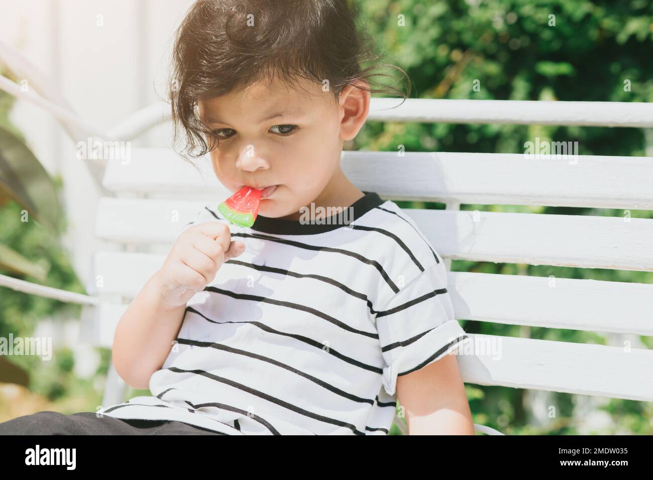 mignon latin enfant indien manger des fruits doux glace assis dehors coloré charmant. Banque D'Images