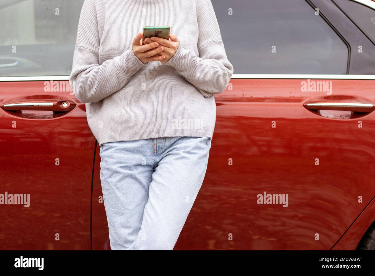 femme devant la porte latérale rouge voiture dans chaud pull-over bleu jeans Banque D'Images