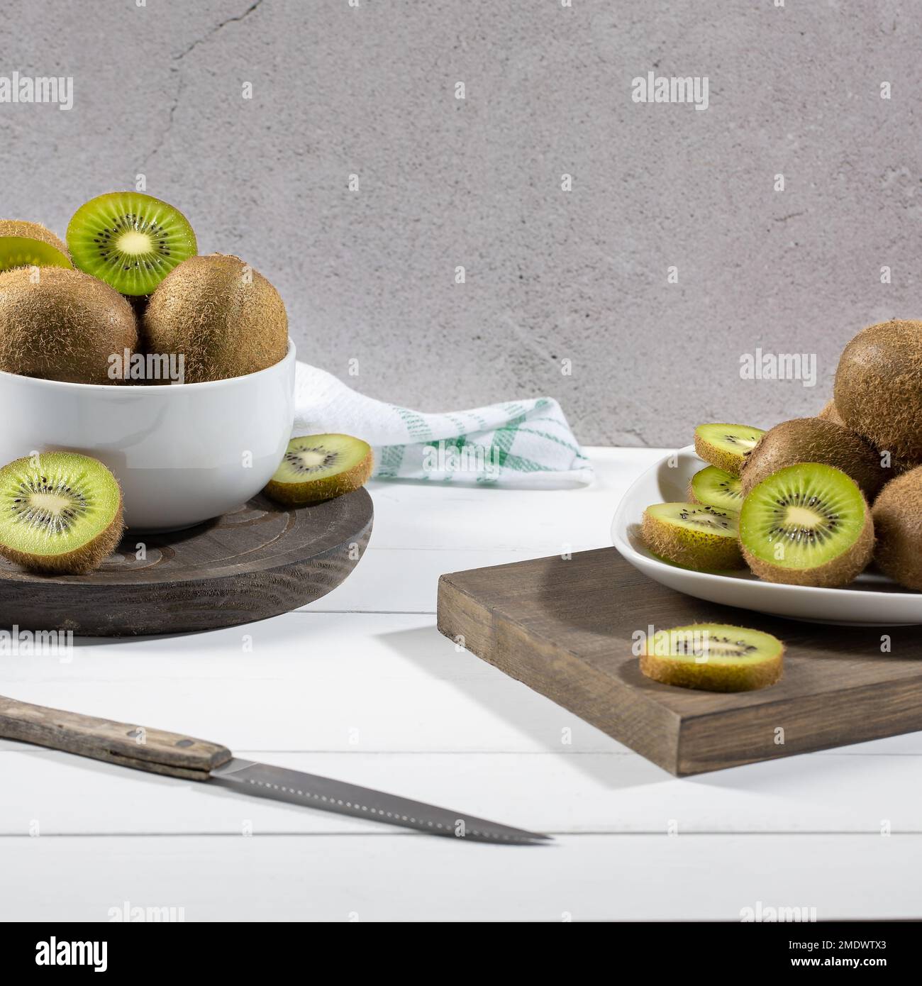 Kiwi frais et tranches sur plaque blanche sur fond clair. Mise au point sélective. Format carré. Banque D'Images