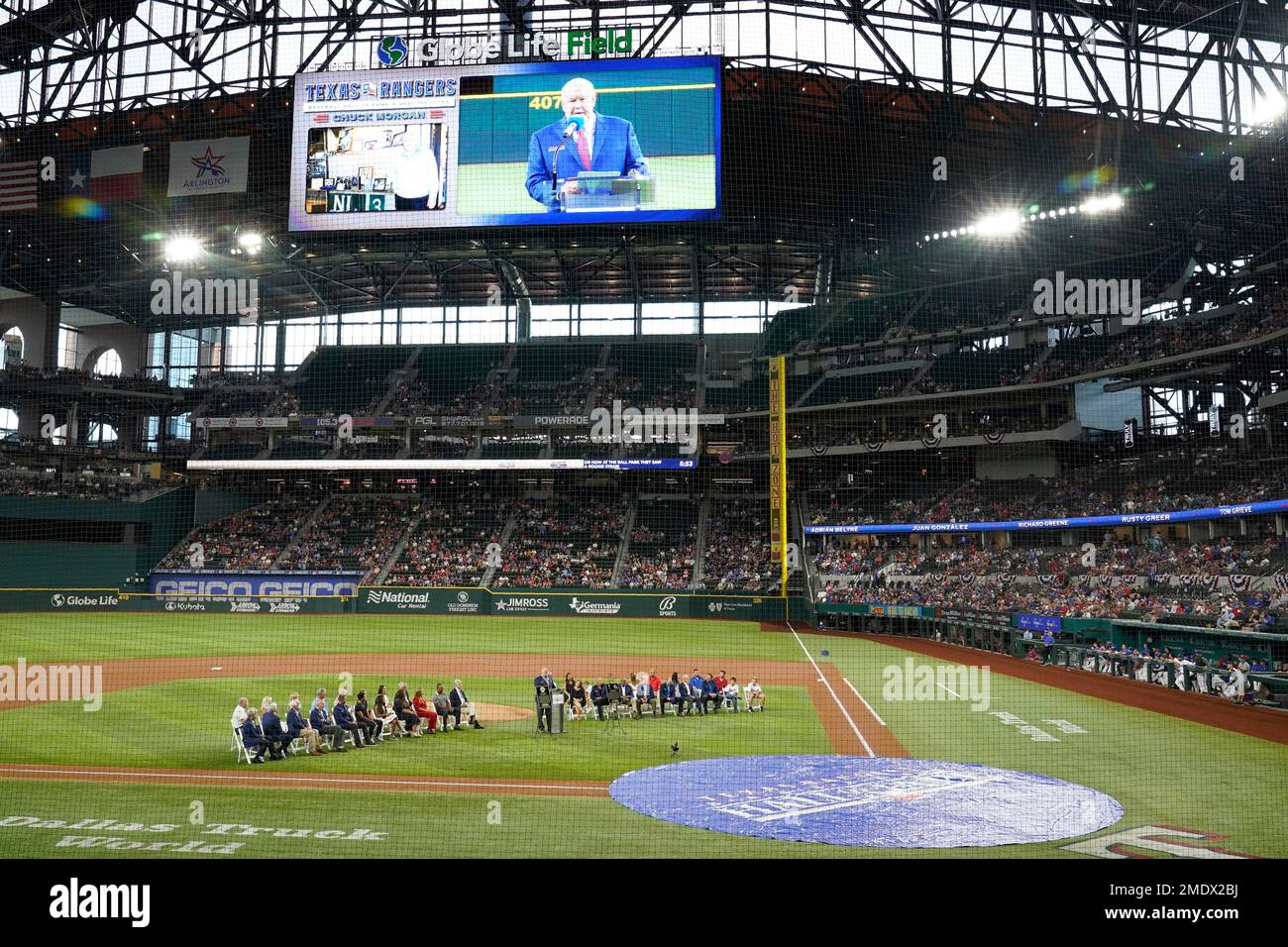 Texas Rangers public address announcer Chuck Morgan stands at a lectern and is displayed on-screen as he speaks during a ceremony before a baseball game against the Oakland Athletics in Arlington, Texas, Saturday, Aug. 14, 2021. Morgan and retired player Adrian Beltre were inducted into the Rangers' Hall of Fame on Saturday. (AP Photo/Tony Gutierrez) Banque D'Images