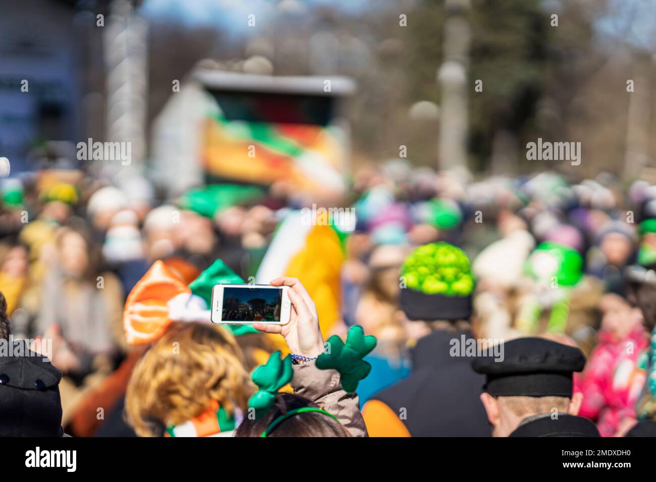 Abstrait brouillé foule de personnes. Mains de fille avec smartphone, St. Carnaval de la Patrick Banque D'Images