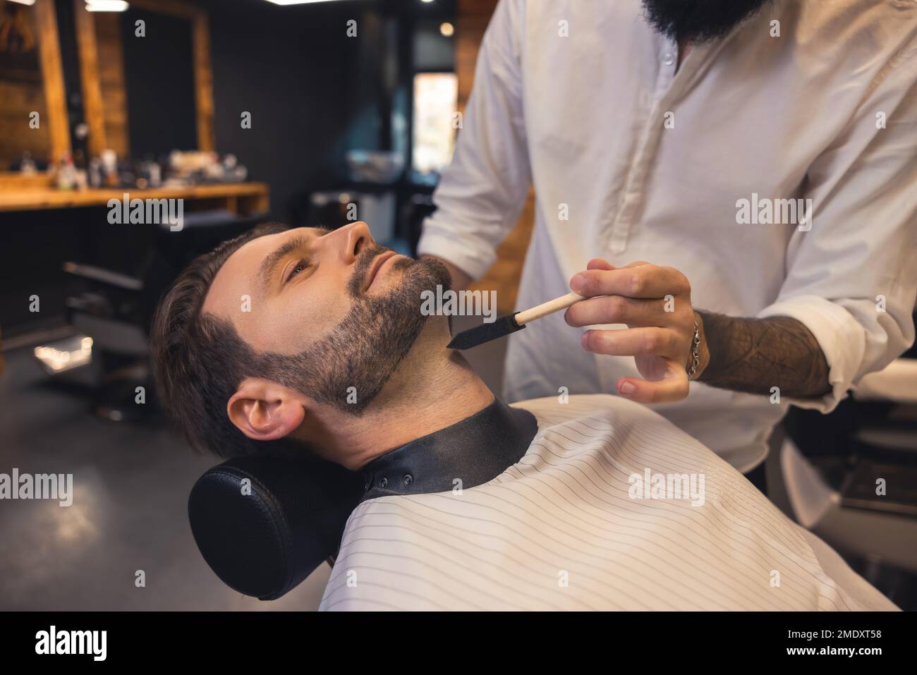 Coiffeur dans le salon de travail sur la barbe des clients Banque D'Images