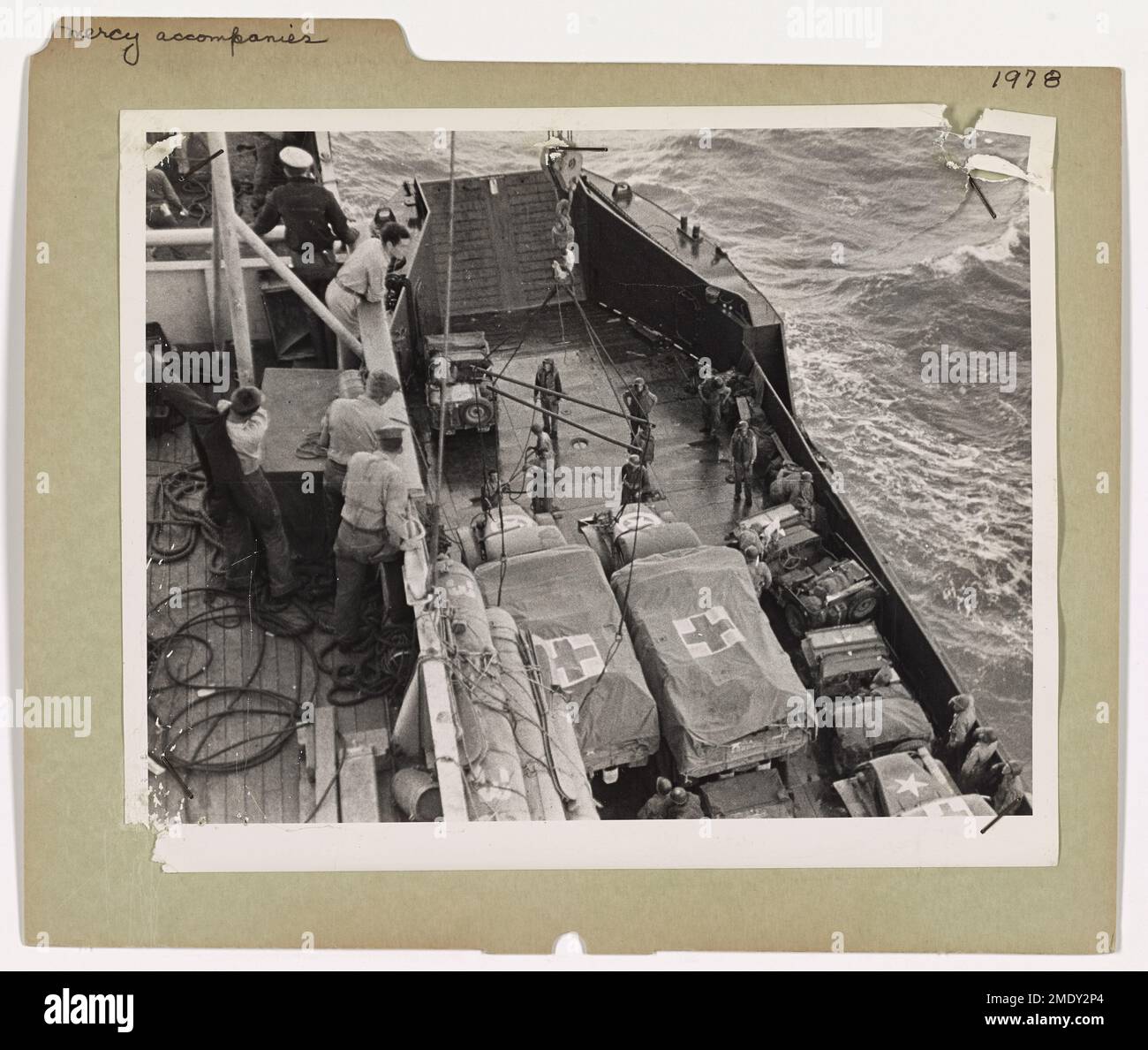Les gardes-côtes abaissent soigneusement les machines Mercy marquées de la Croix-Rouge d'un navire de transport habité par les gardes-côtes dans une embarcation d'invasion. Ces véhicules, marqués pour usage médical, accompagnent les troupes lors des invasions pour fournir des soins immédiats aux blessés. Banque D'Images