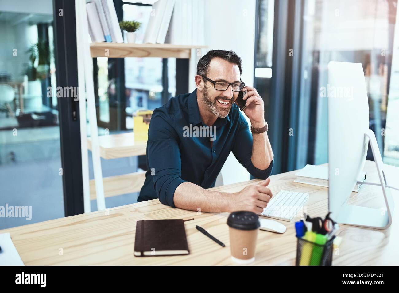 C'est toujours bon faire des affaires avec vous. un homme d'affaires mature parlant au téléphone tout en étant assis à son bureau. Banque D'Images