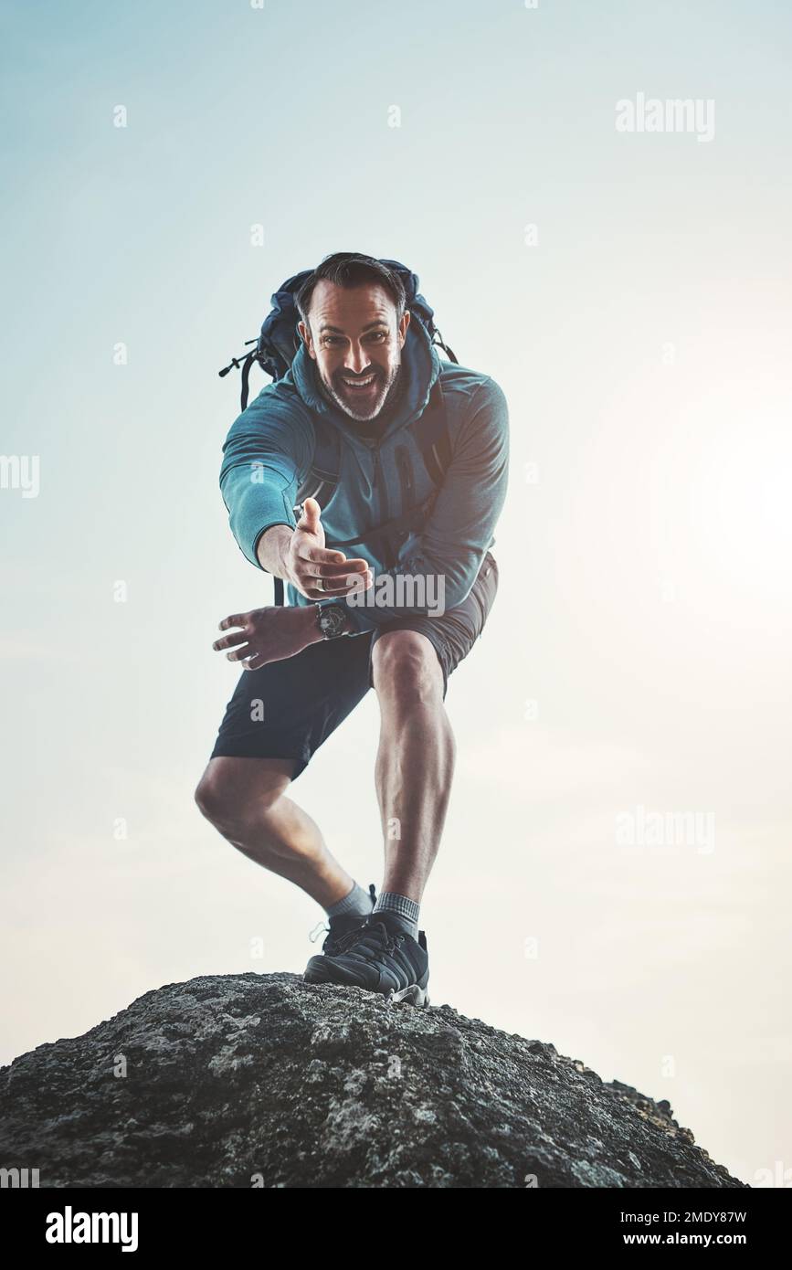 Prenez ma main et partez à la conquête du monde ensemble. Portrait à angle bas d'un homme d'âge moyen debout sur un rocher et en train d'atteindre sa main. Banque D'Images