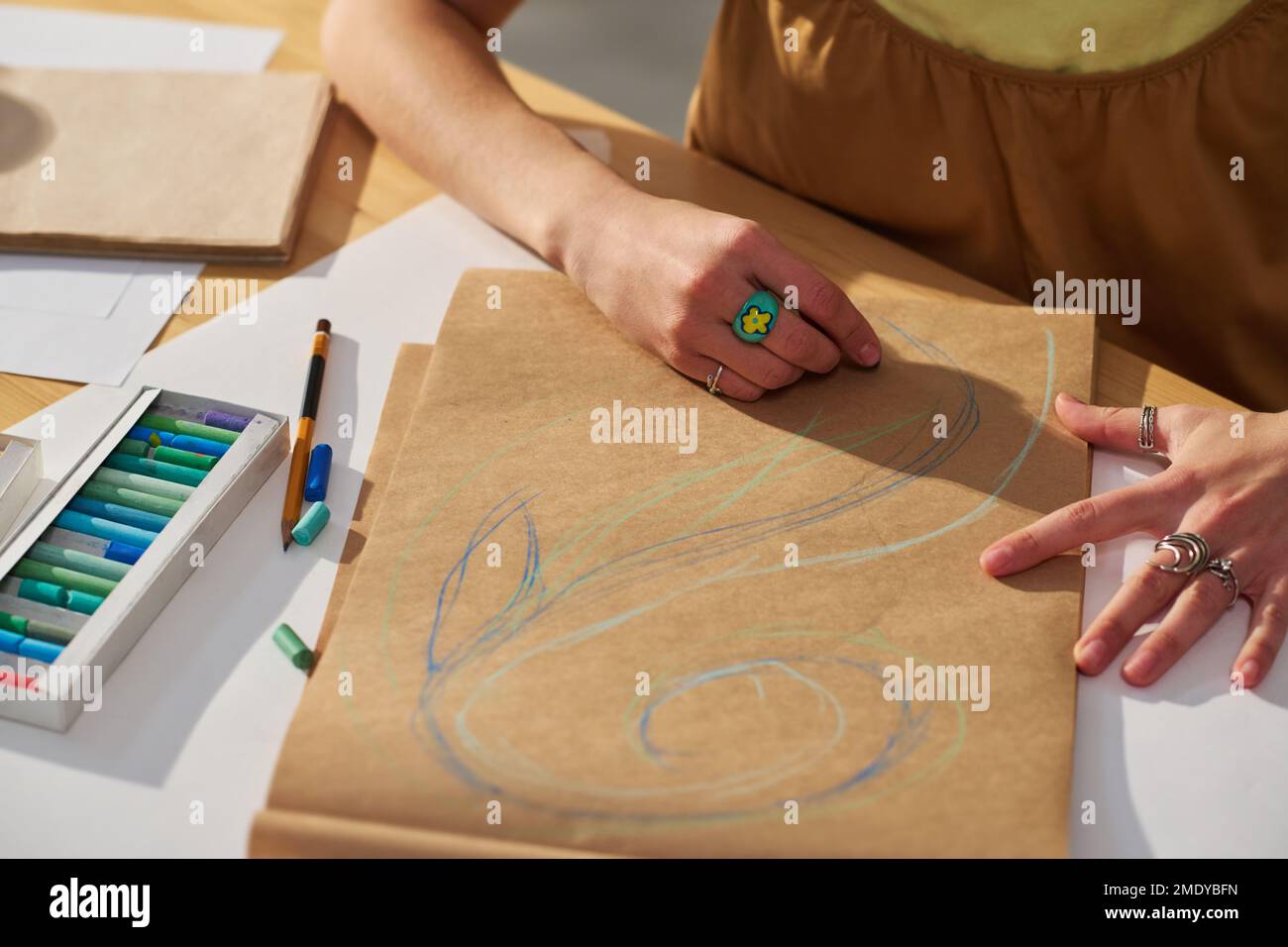 Gros plan d'une jeune femme créative qui dessine des croquis sur papier au crayon bleu tout en étant assise sur le lieu de travail dans un studio à domicile Banque D'Images