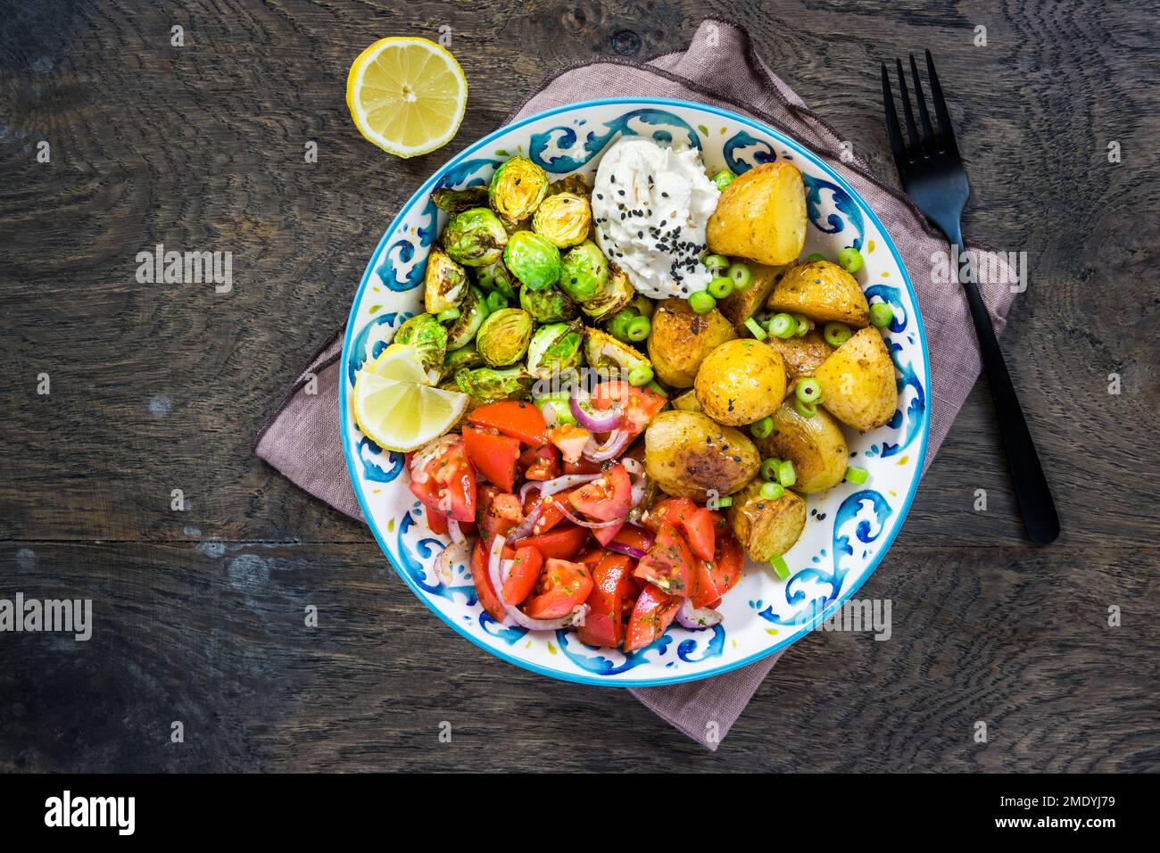 Choux de Bruxelles et saladier à la tomate, aliments sains et équilibrés avec pommes de terre cuites au four Banque D'Images