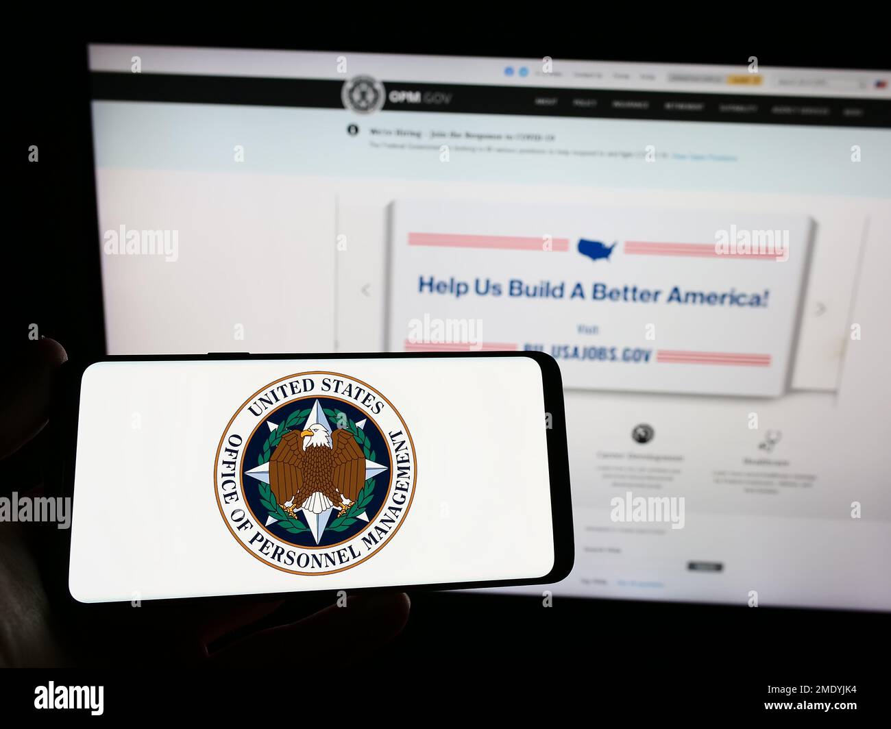 Personne tenant un smartphone avec le sceau de l'Office of personnel Management (OPM) des États-Unis sur l'écran devant le site Web. Mise au point sur l'affichage du téléphone. Banque D'Images