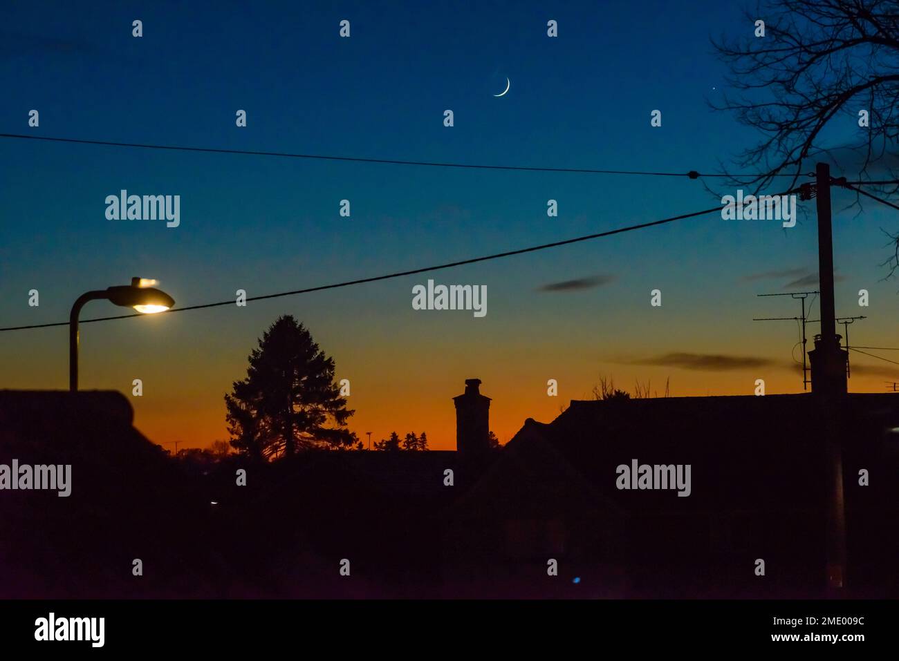 Fordingbridge, Hampshire, Angleterre, Royaume-Uni, 23 janvier 2023, météo : horizon orange brillant sur les toits après le coucher du soleil, car la température descend en dessous du point de congélation. Banque D'Images