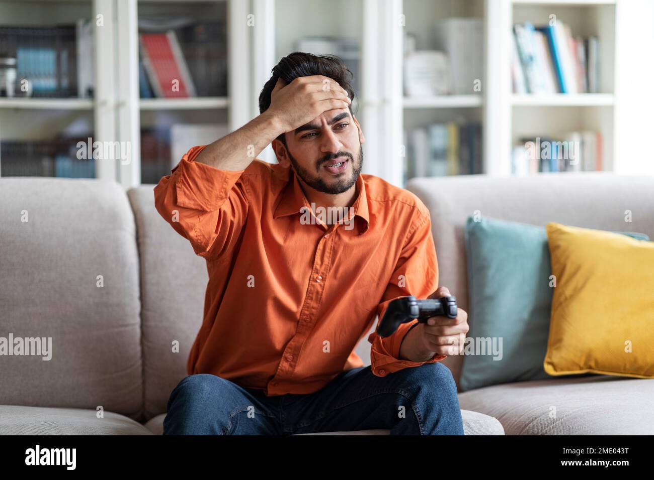 Triste homme arabe jouant à des jeux vidéo à la maison, en tenant le joystick Banque D'Images