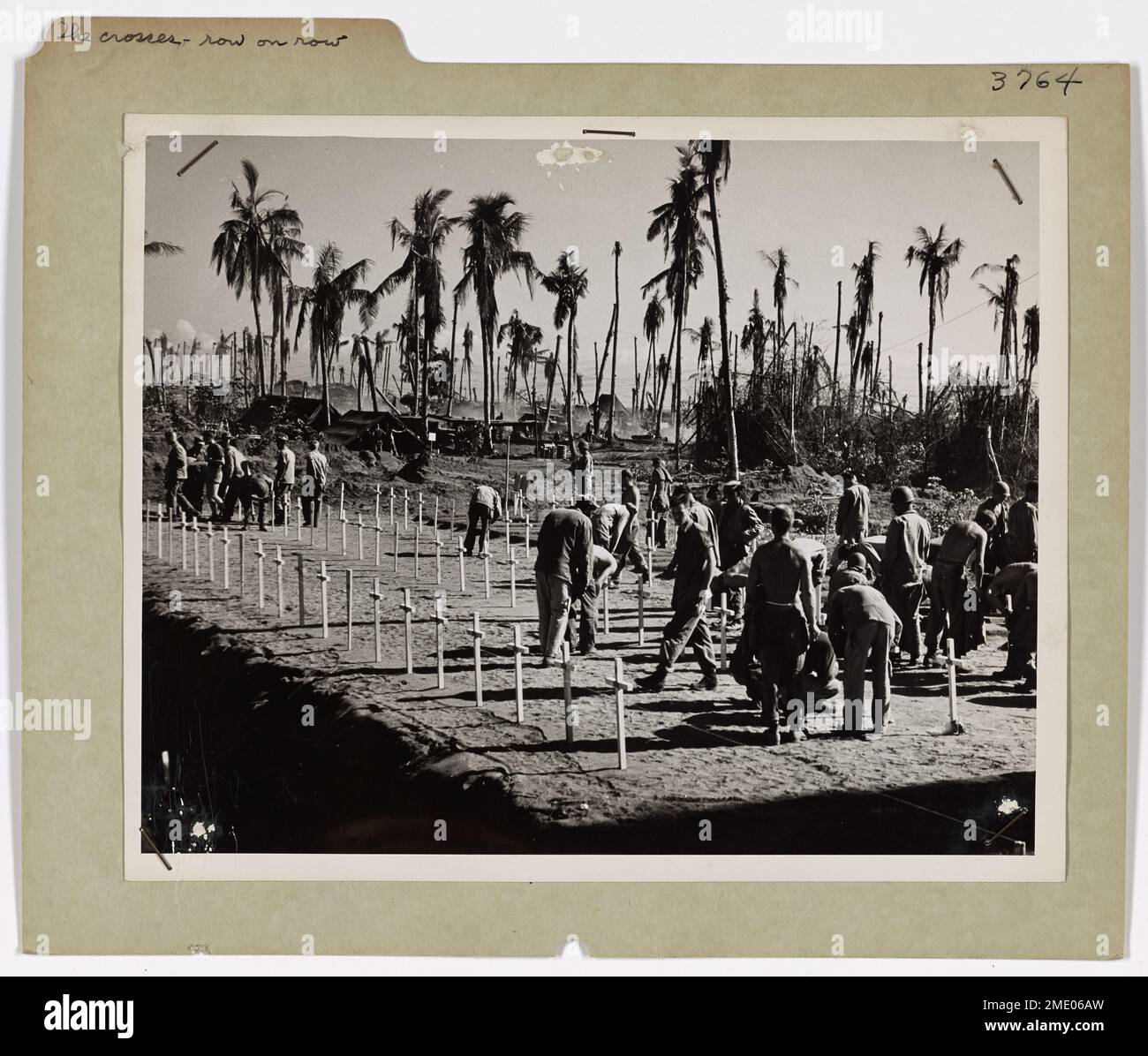 Les soldats et les gardes-côtes recherchent les noms des camarades tombés au cimetière américain sur l'île de Leyte. Les rangées de croix marquent les tombes de ceux qui ont donné leur vie pendant la libération des Philippines. Un aumônier vient de terminer les services funéraires sous les palmiers, un rappel solennel du sacrifice consenti pendant la seconde Guerre mondiale. Banque D'Images