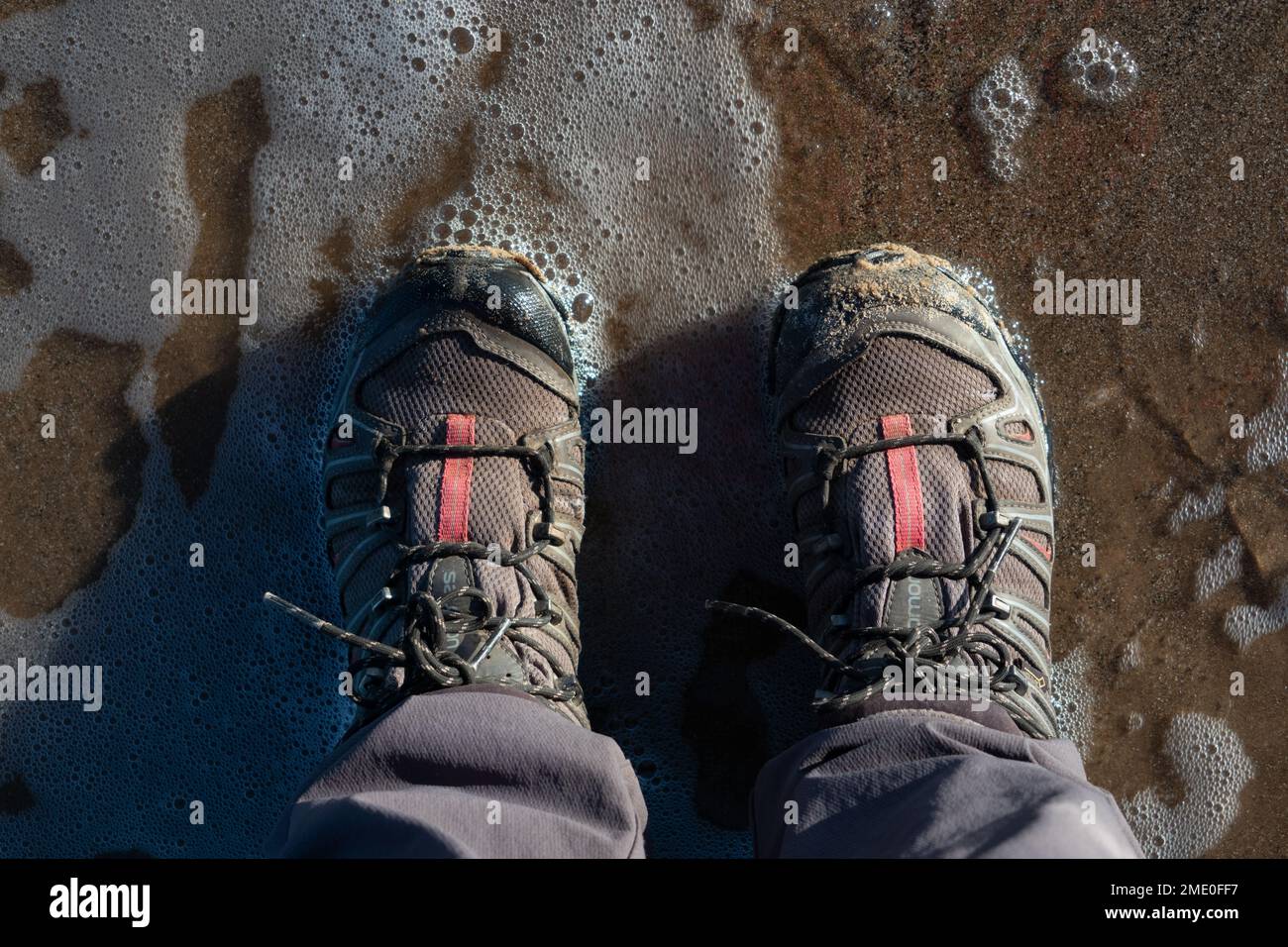 Bottes de marche sur la plage iat bord de mer Angleterre, vue vers le bas Banque D'Images