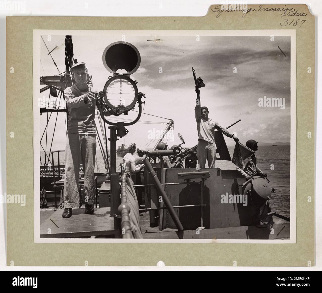 Cette image montre des gardes-côtes transmettant des ordres d'invasion en utilisant des signaux clignotants et des drapeaux sémaphores sur le pont de signalisation d'un transport de combat habité par les gardes-côtes américains. Ces méthodes de communication étaient essentielles pour coordonner les débarquements lors des invasions du Pacifique. Banque D'Images
