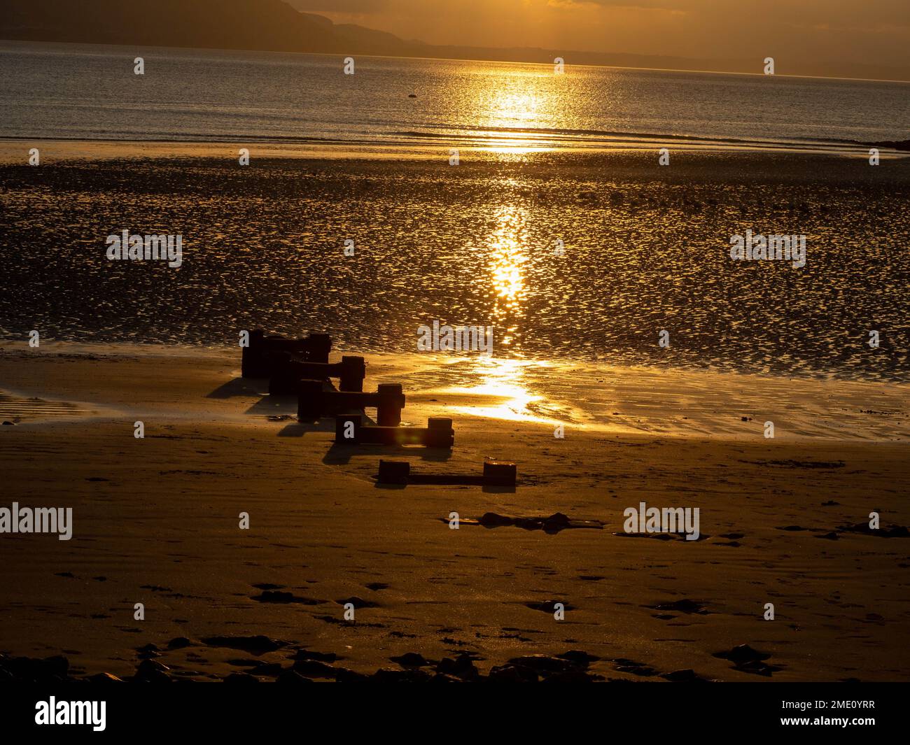 Groynes sur la plage de Llandudno dans le nord du pays de Galles comme les couchers de soleil sur la mer d'Irlande Banque D'Images