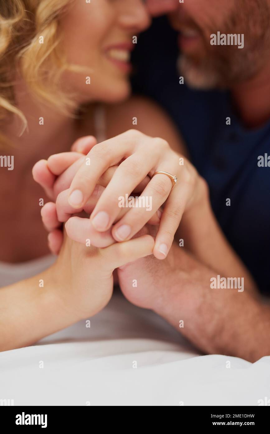 La fidélité est une belle chose. un heureux couple d'âge moyen tenant les mains et se relaxant dans le lit ensemble. Banque D'Images