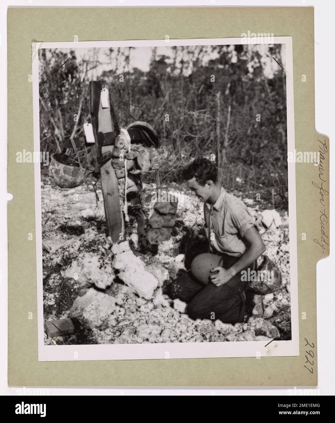 Le garde-côtes James Fulton s'agenouille à côté de la tombe d'un ami des Marines mort lors de la bataille de Peleliu, une campagne cruciale du Pacifique. Fulton honore son camarade déchu en dressant une croix et en plaçant la ceinture et le casque du Marine. Banque D'Images
