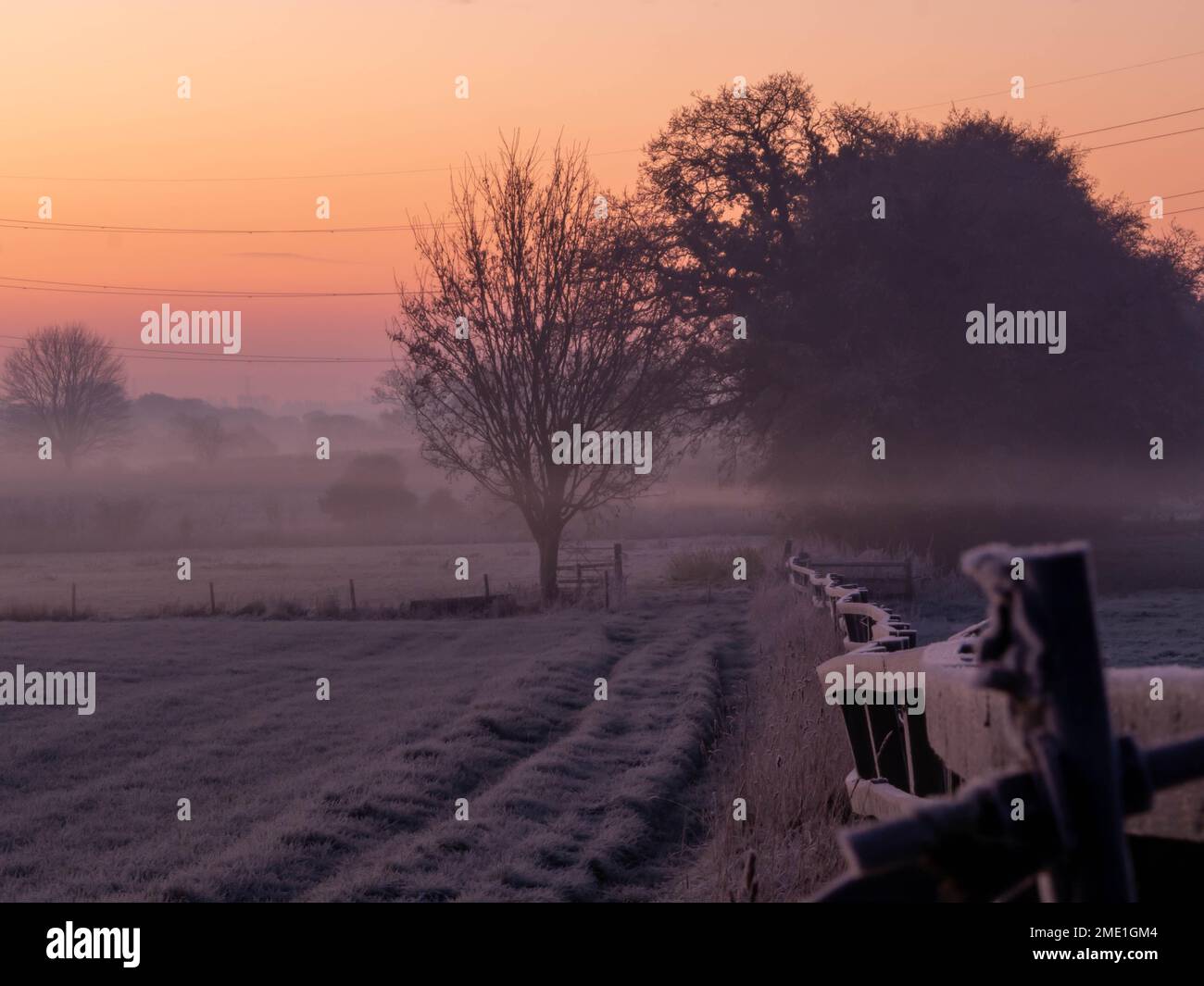 Lueur orange du lever du soleil lors d'une matinée froide et givrée avec une brume basse au-dessus des champs du Cheshire oriental Banque D'Images