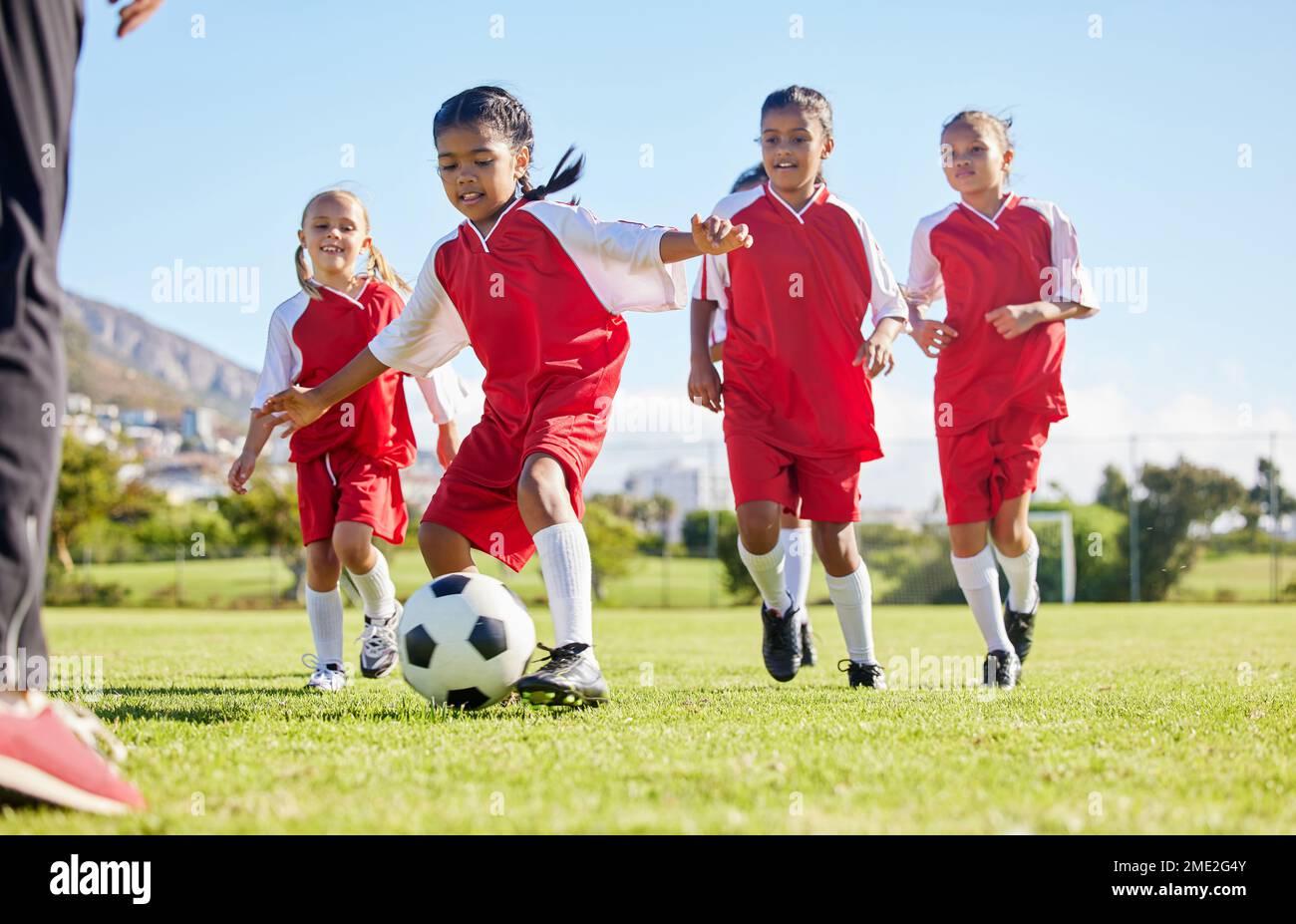 Le football, le ballon ou le sport et une équipe de filles s'entraînent ou jouent ensemble sur un terrain d'entraînement. Fitness, football et herbe avec les enfants en train de courir ou Banque D'Images