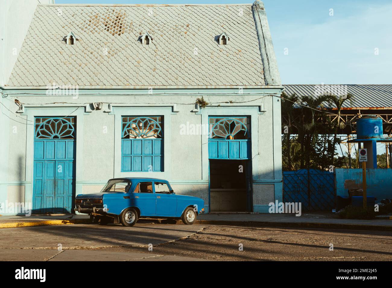 Extérieur de la maison ancienne avec portes bleues et vieille voiture garée de couleur bleue à proximité sur le trottoir Banque D'Images