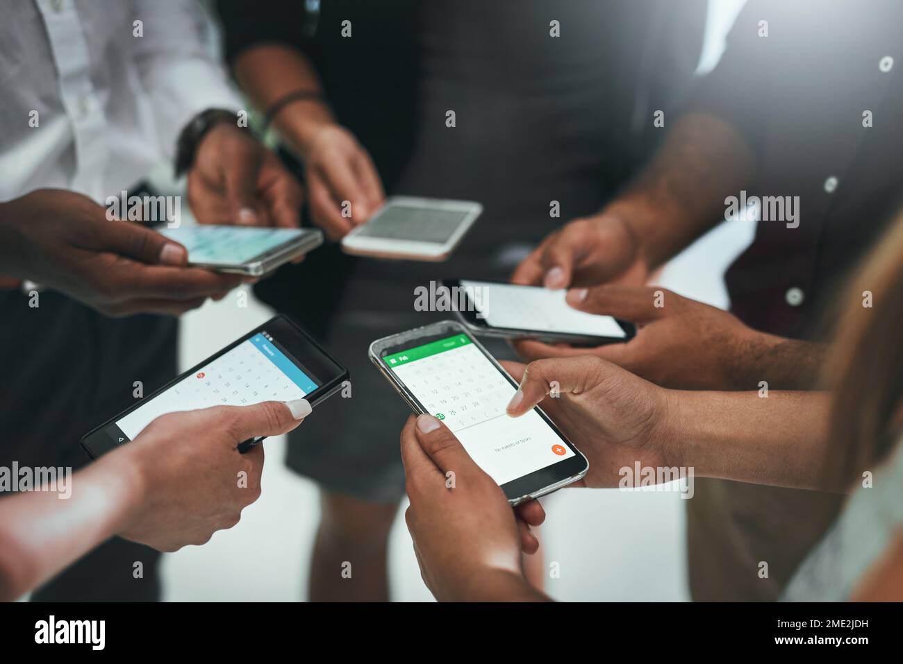 Restez connecté au réseau de votre entreprise. un groupe d'hommes et de femmes d'affaires qui utilisent leur téléphone portable ensemble. Banque D'Images
