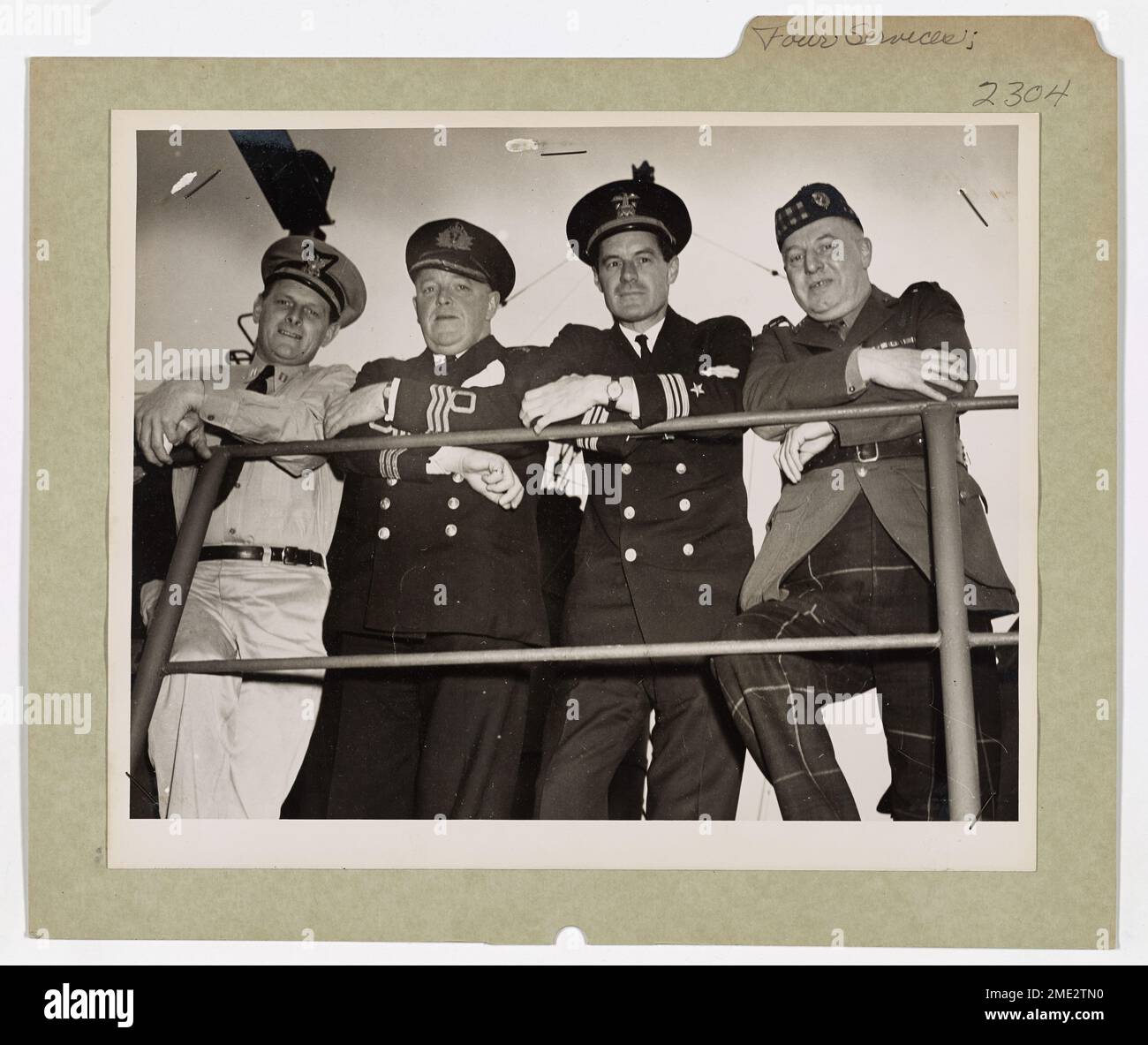 Des officiers de la Garde côtière américaine, de la Marine américaine, de la Royal Navy britannique et de la réserve de volontaires de la Royal Navy se tiennent unis sur le pont d'un LST habité par les garde-côtes dans un port anglais. Leur mission collective est la victoire dans la lutte contre l'Allemagne pendant la seconde Guerre mondiale. Banque D'Images