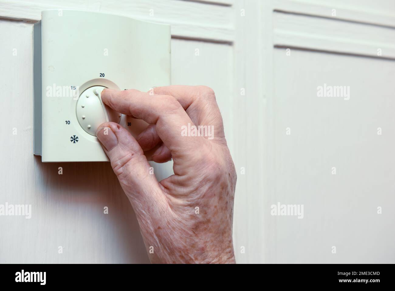 Une femme mature éteint le chauffage central à la maison pour économiser de l'argent Banque D'Images