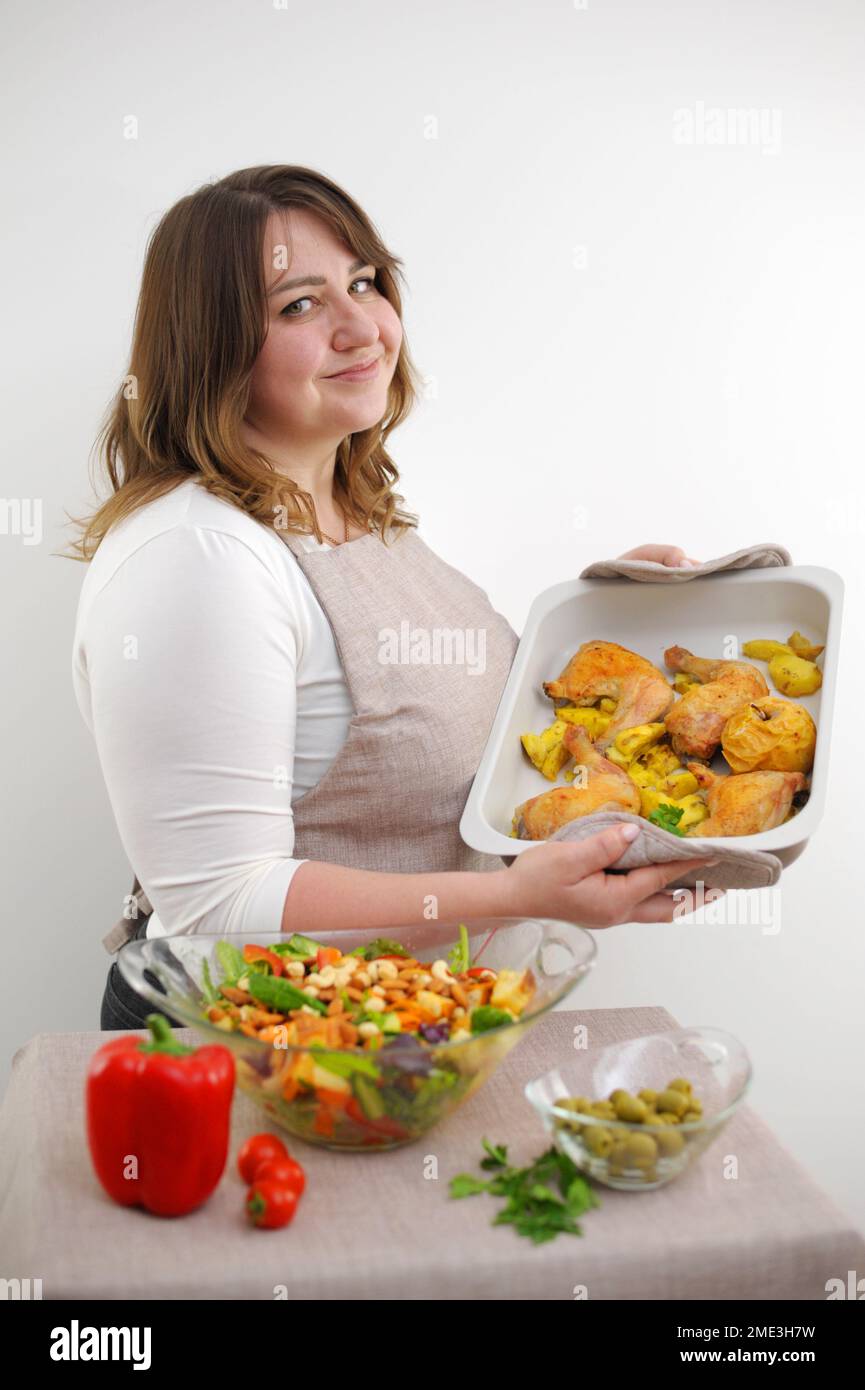 Jeune femme souriante servant de la salade fraîche sur l'assiette. Bonne souriante mignonne femme cuisant une salade végétalienne fraîche et saine à la maison avec de nombreux légumes dans la cuisine et essayant une nouvelle recette photo de haute qualité Banque D'Images
