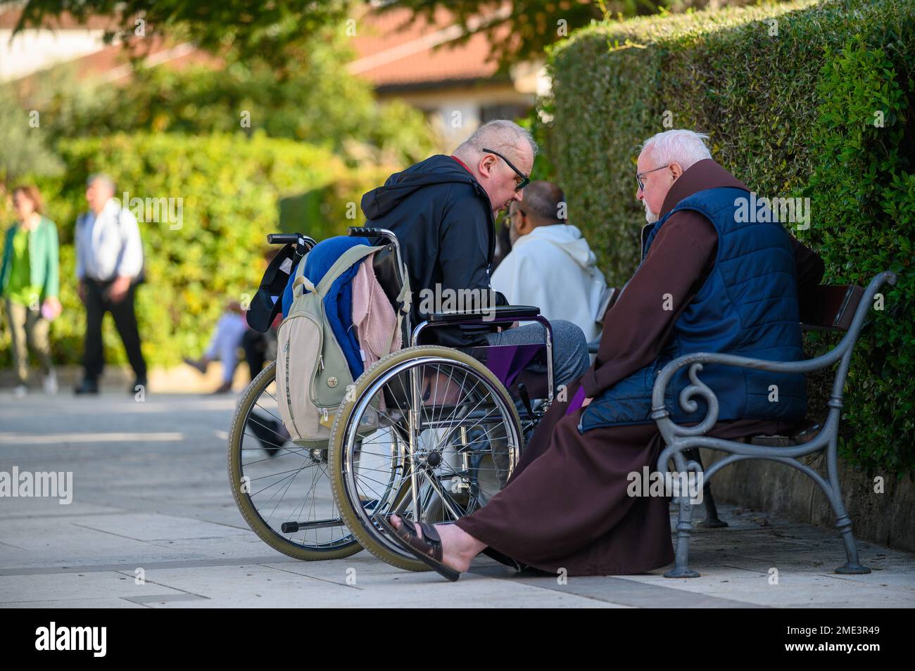 Confession catholique – un homme en fauteuil roulant confessant à un prêtre catholique, franciscain, à Medjugorje. Banque D'Images