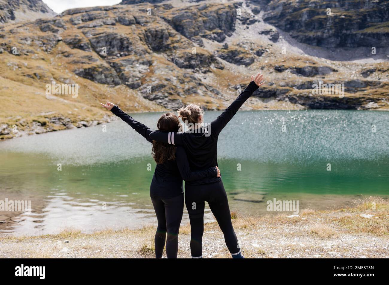 Randonneurs s'embrassant debout avec les bras levés près du lac Banque D'Images