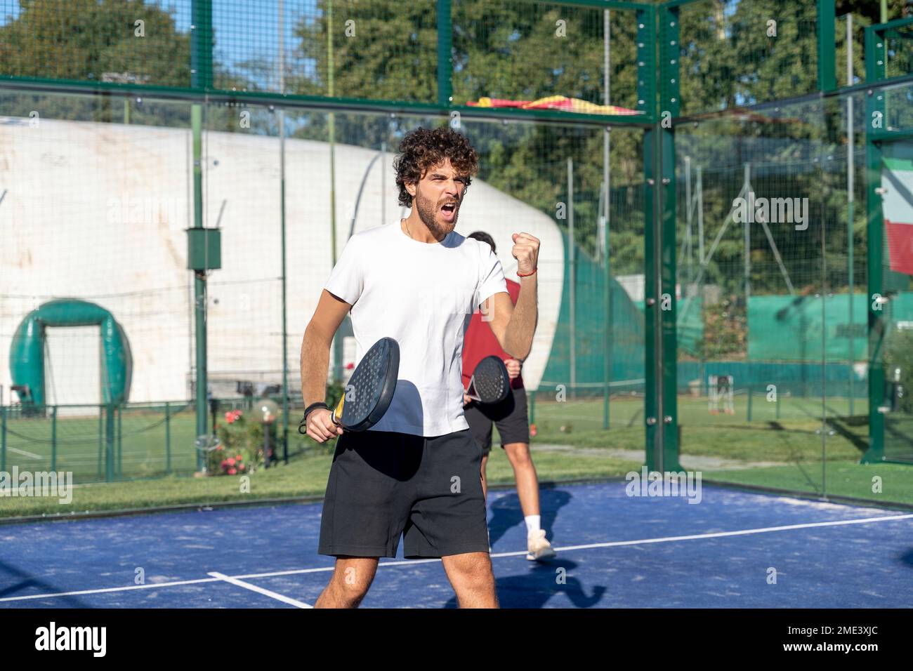 Homme criant avec une raquette de paddle-tennis sur le terrain de sport Banque D'Images