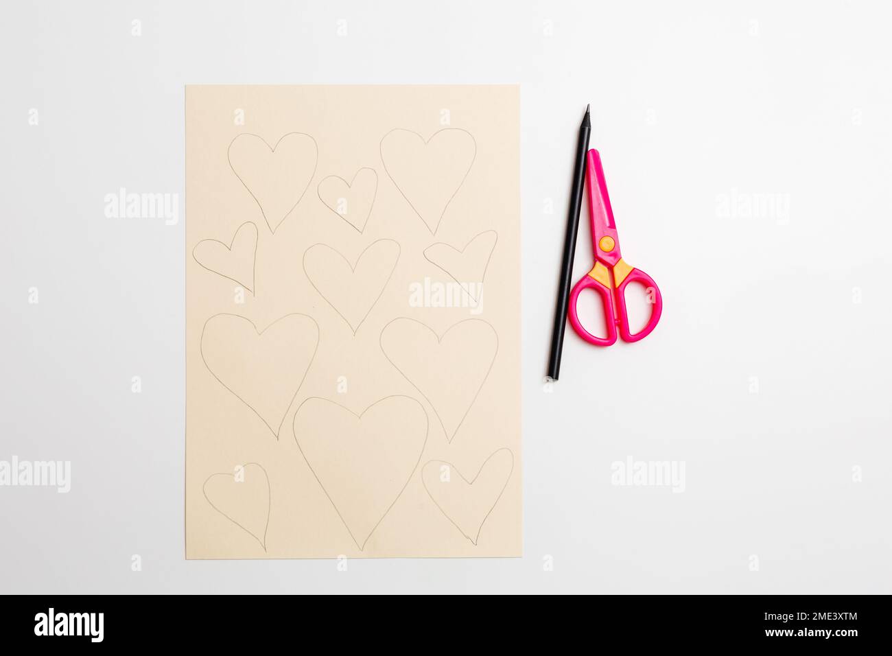 Comment faire un coeur en papier mignon pour la Saint Valentin. Projet d'art pour enfants. Instructions détaillées sur la photo. Étape 1. Dessinez les coeurs sur le papier à l'aide d'un crayon Banque D'Images