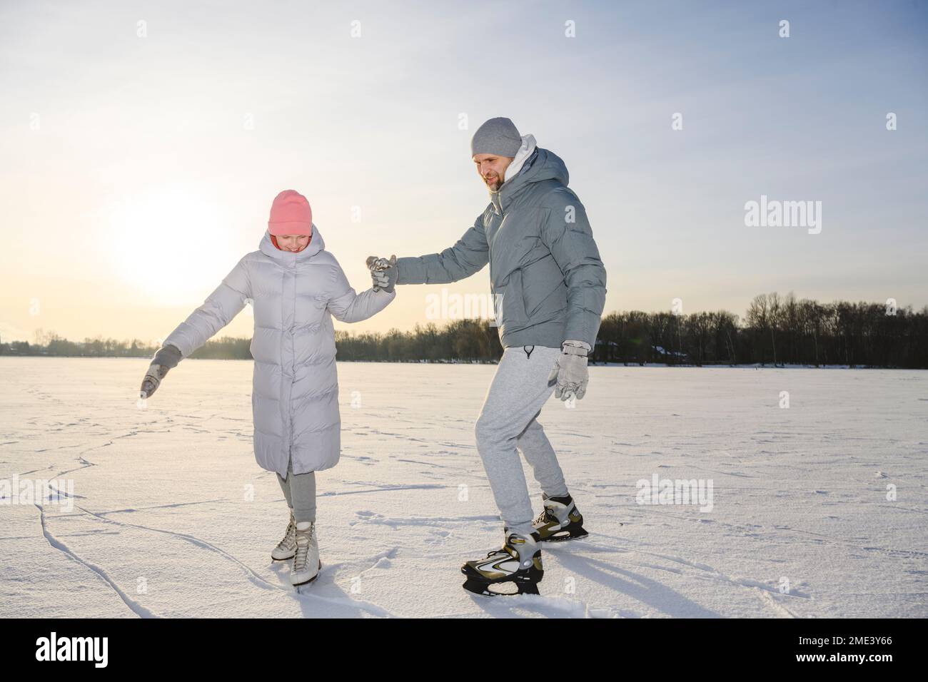 Fille heureuse avec père pratiquant le patinage sur glace sur le lac d'hiver Banque D'Images