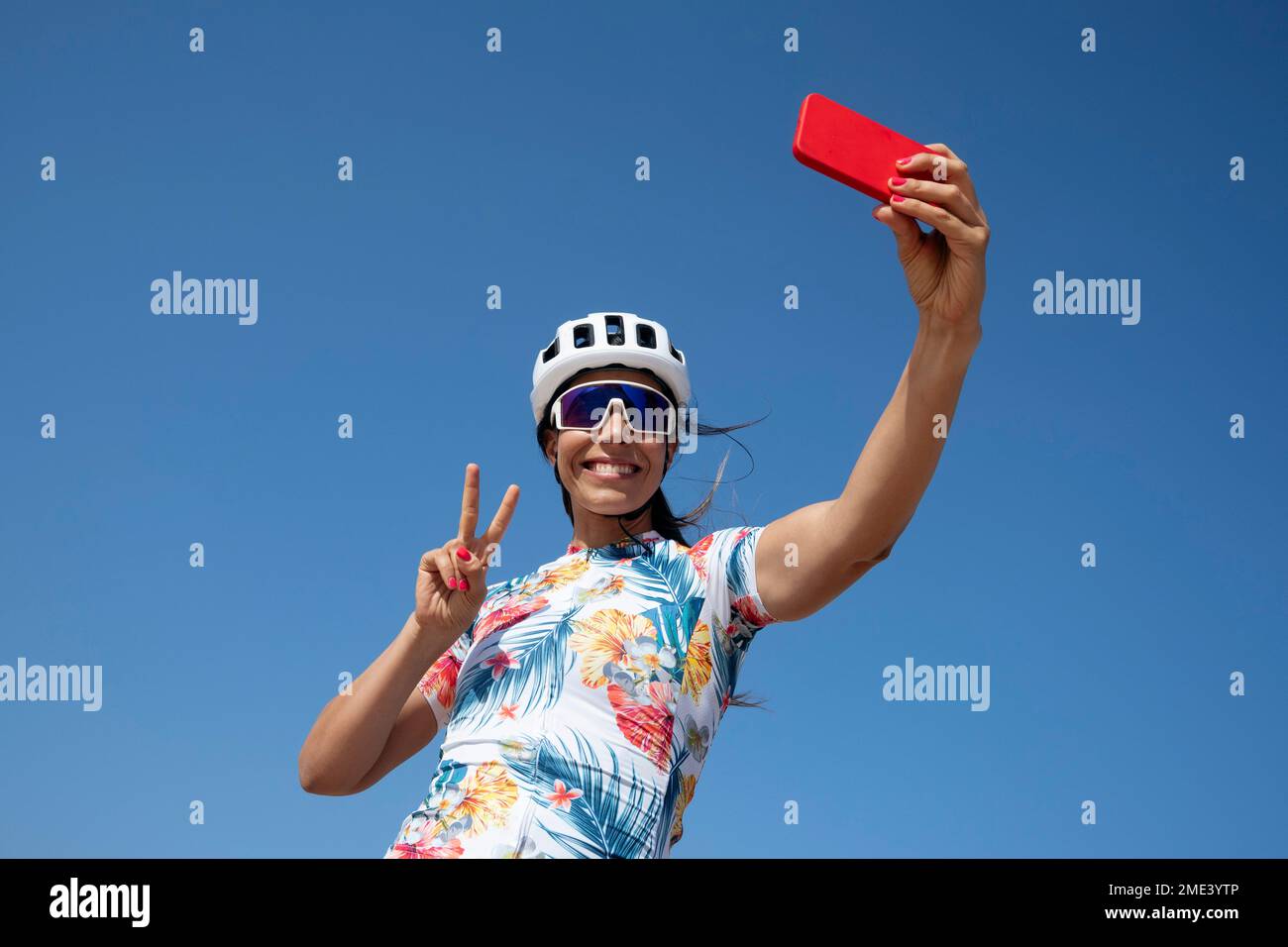Cycliste heureux montrant le geste de la paix et prenant le selfie par téléphone intelligent Banque D'Images