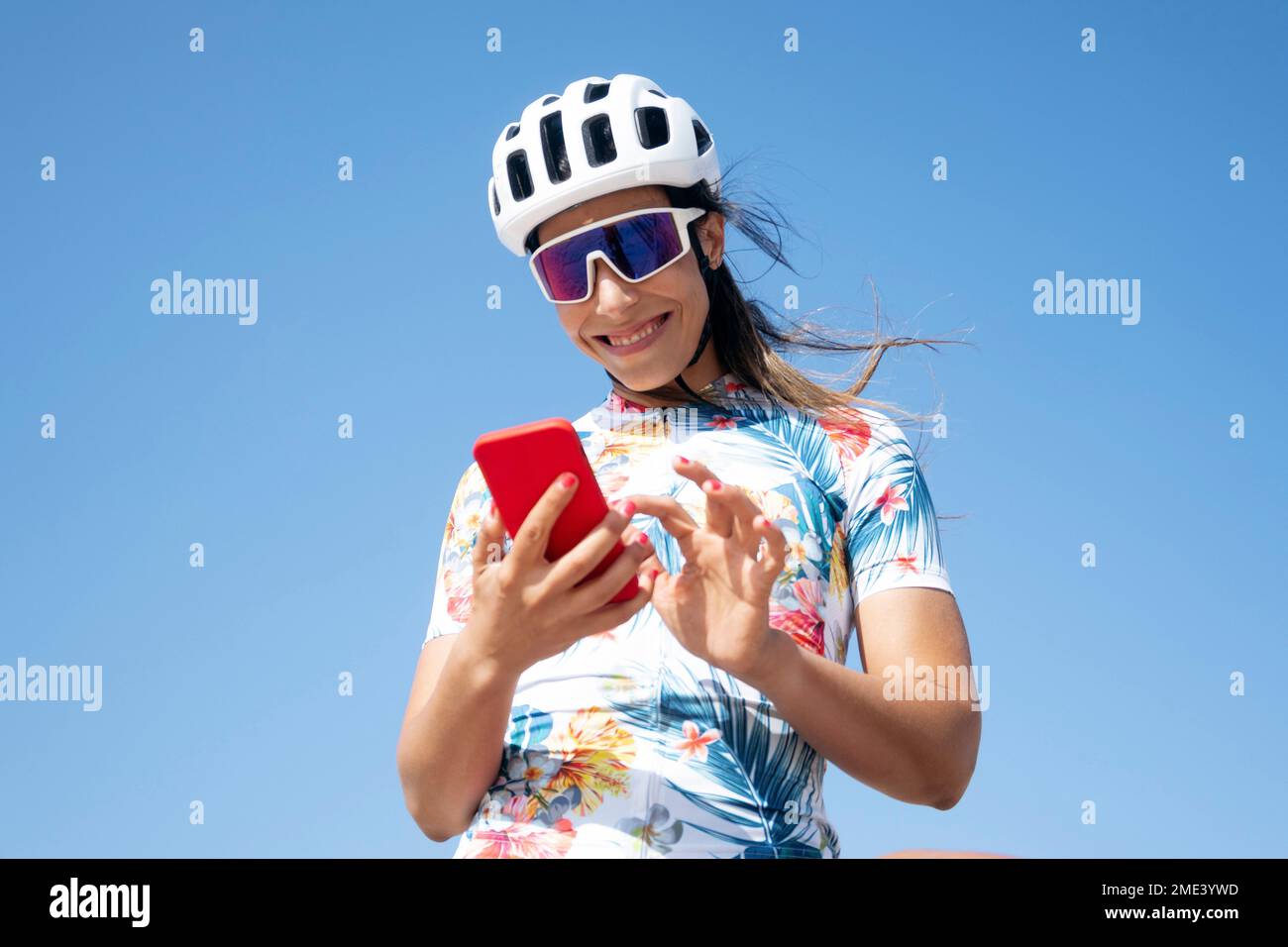 Cycliste heureux en utilisant un smartphone sous le ciel Banque D'Images