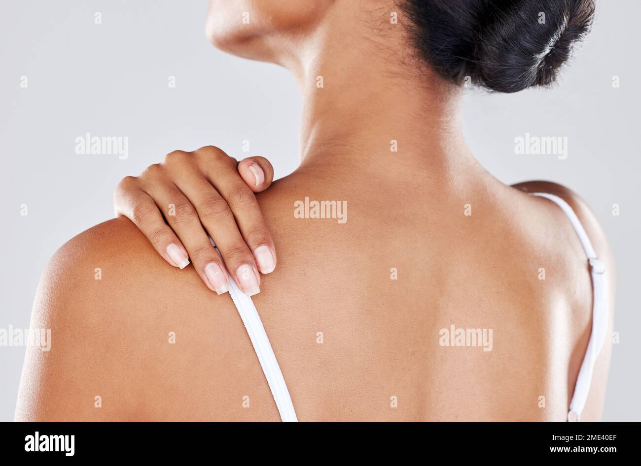 Douleur à l'épaule, blessure et main de femme sur le dos due à la douleur, l'inflammation ou la tension musculaire isolée dans un fond gris studio. Stress, spa et Banque D'Images