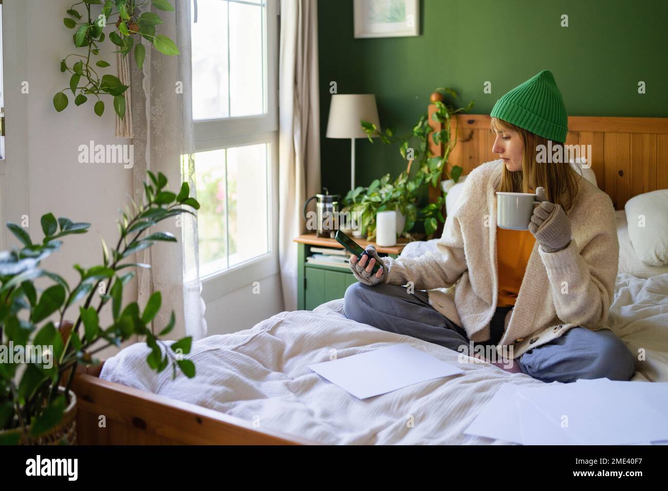 Femme avec des factures financières utilisant un smartphone à la maison Banque D'Images