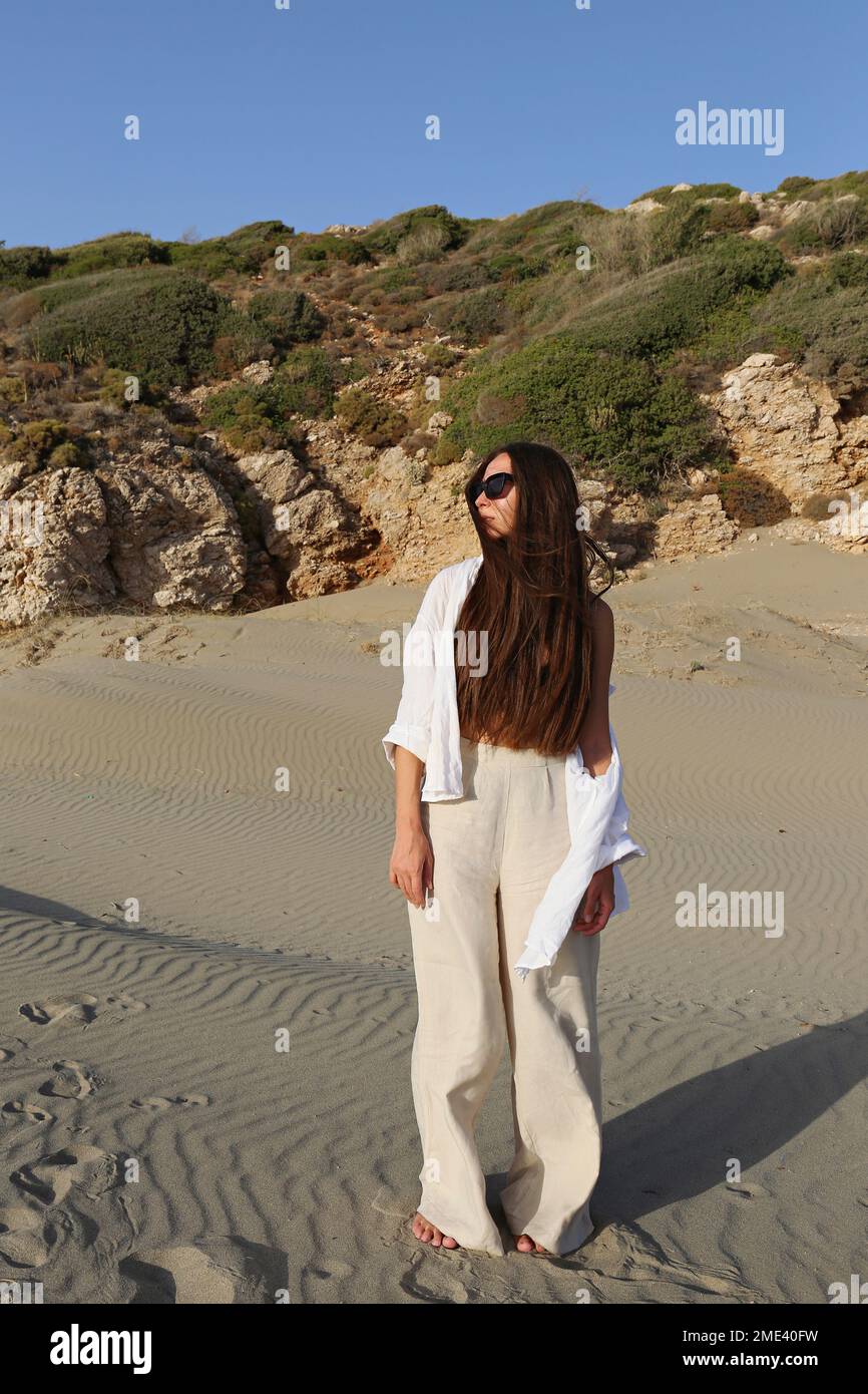 Jeune femme avec de longs cheveux debout sur le sable à la plage, Patara, Turkiye Banque D'Images