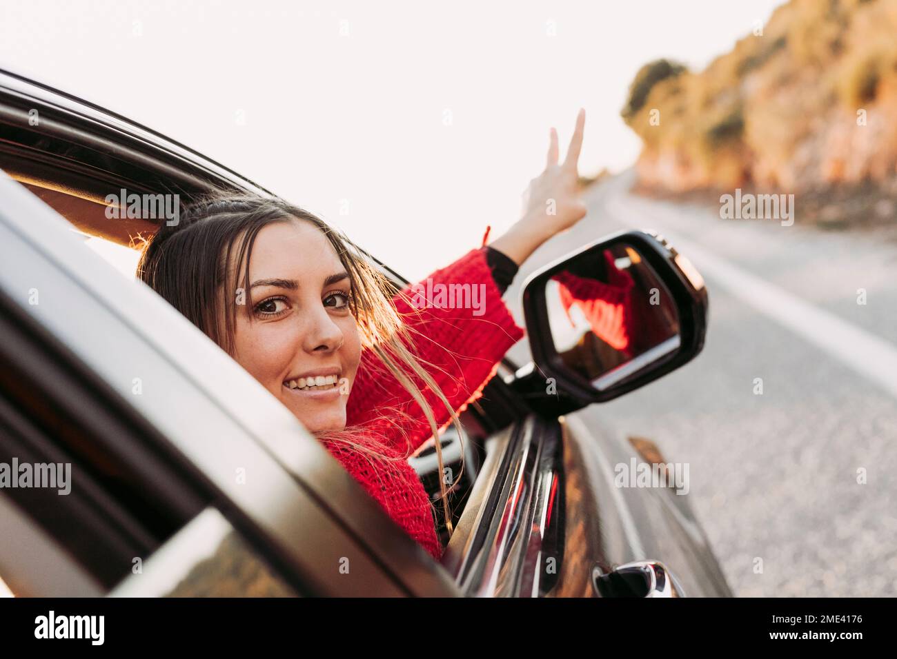 Femme en voiture regardant la caméra pointant sur la route Banque D'Images