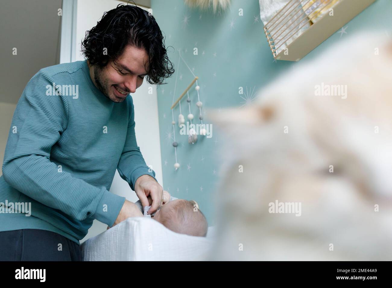 Joyeux père changeant les vêtements de bébé garçon à la maison Banque D'Images