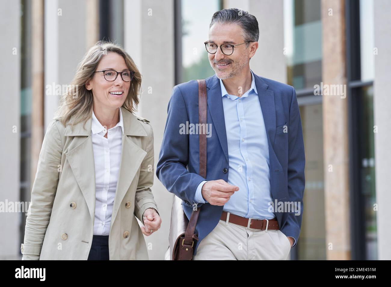 Des gens d'affaires heureux et mûrs se promenant ensemble à l'extérieur du bâtiment Banque D'Images Des gens d'affaires heureux et mûrs se promenant ensemble à l'extérieur du bâtiment Banque D'Images