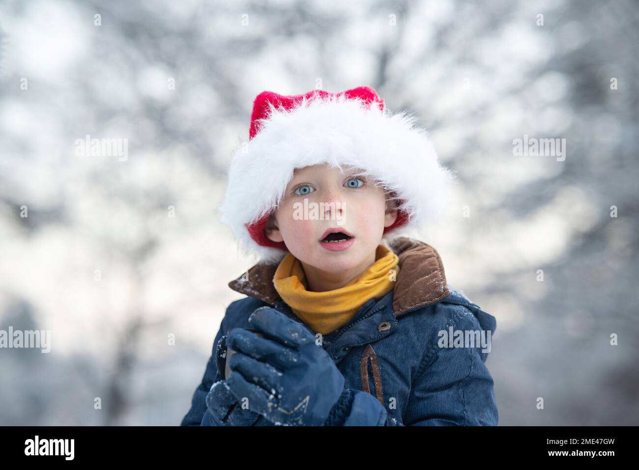 Un adorable garçon surpris portant un chapeau de père Noël Banque D'Images