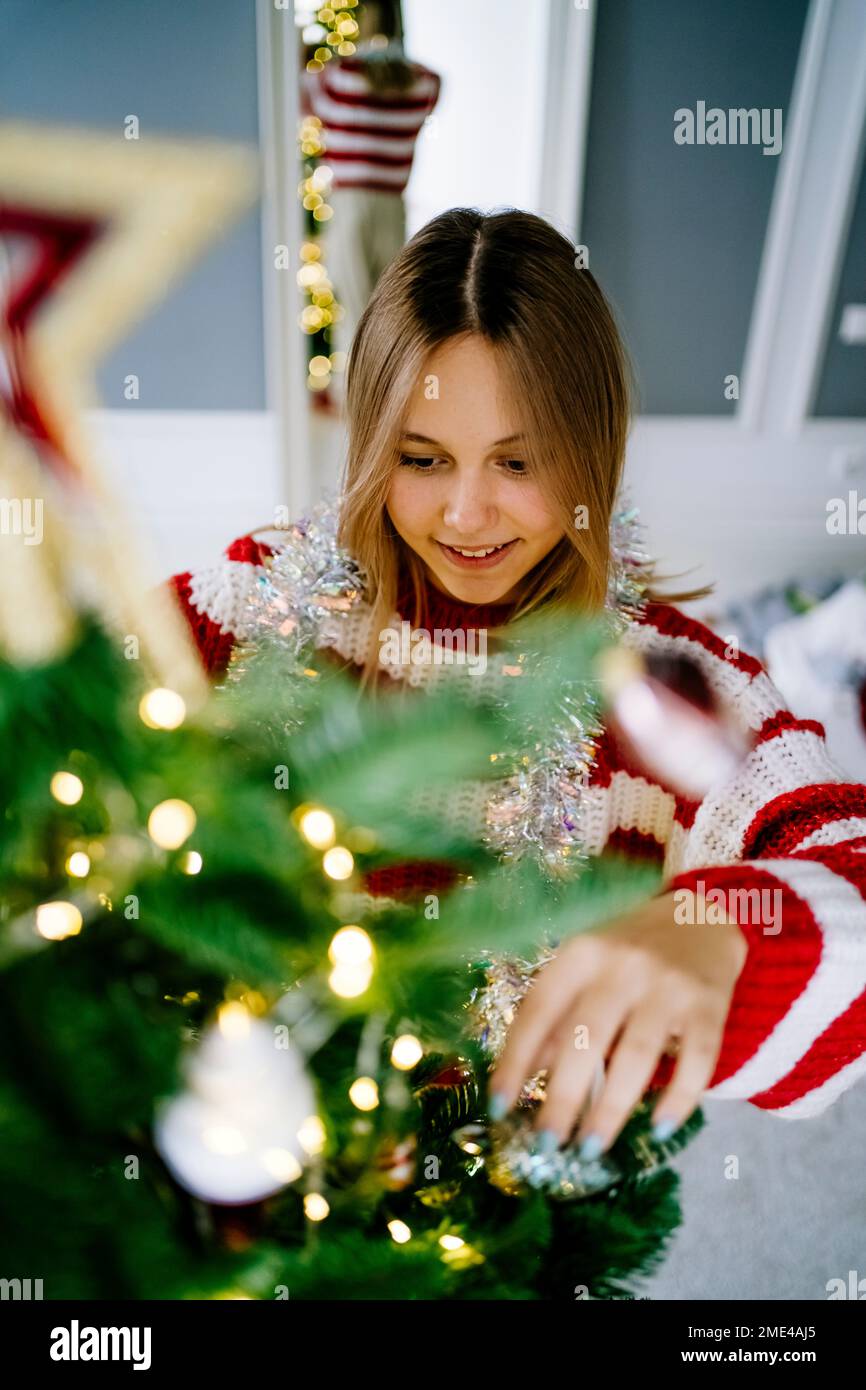 Fille souriante décorant l'arbre de Noël à la maison Banque D'Images