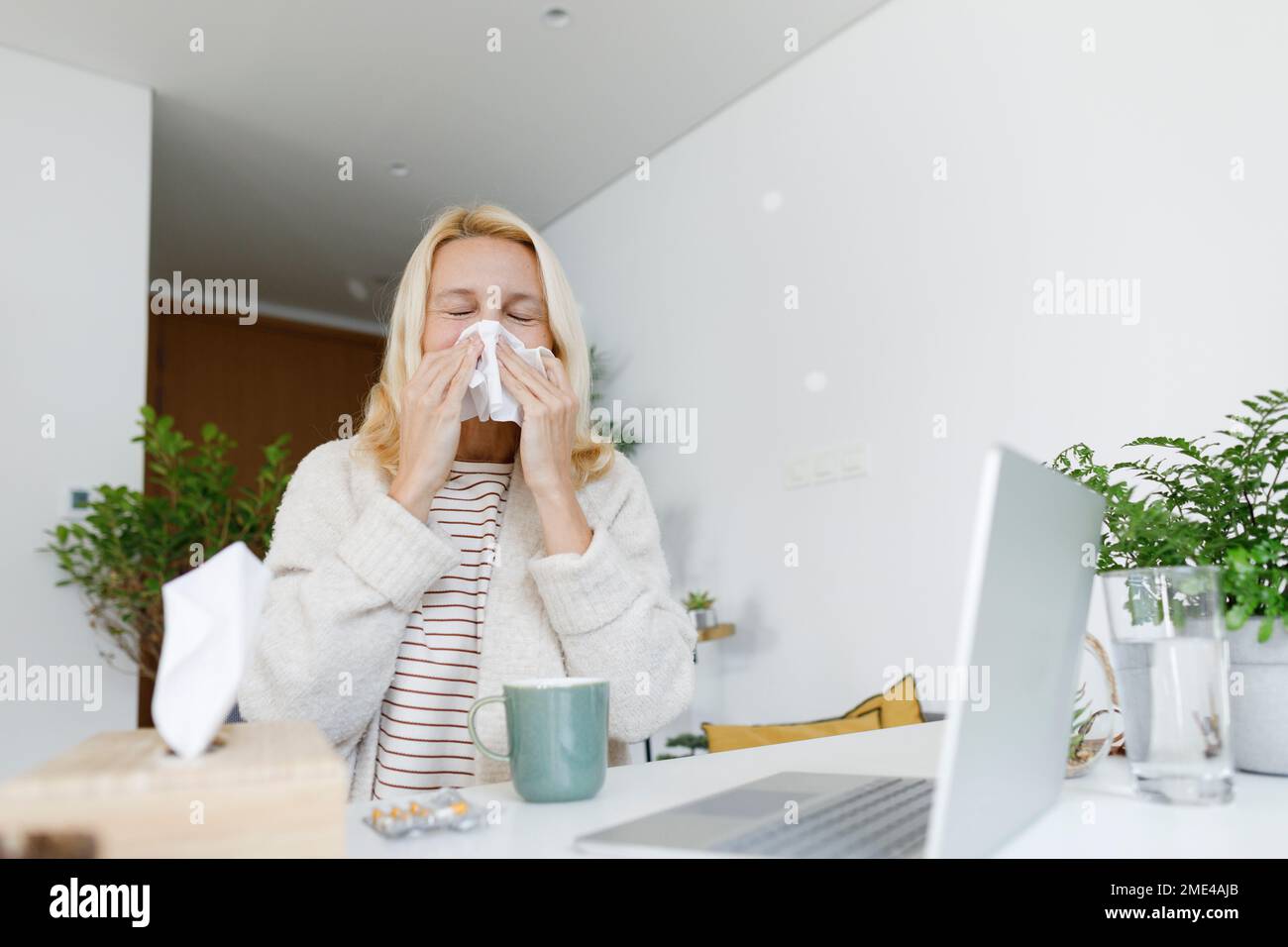 Malade indépendant éternuant sur papier de soie assis à la maison Banque D'Images