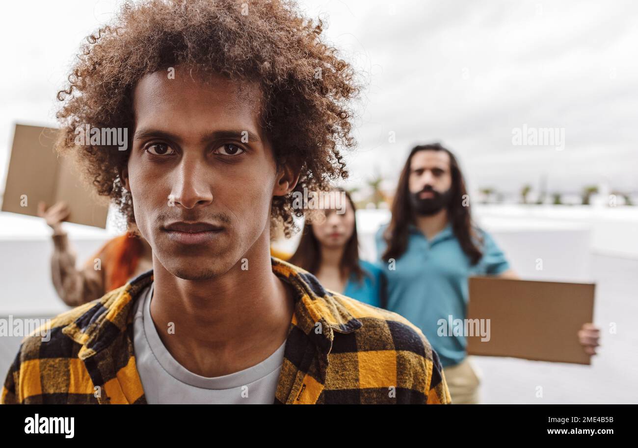 Jeune homme sérieux avec des manifestants en arrière-plan Banque D'Images