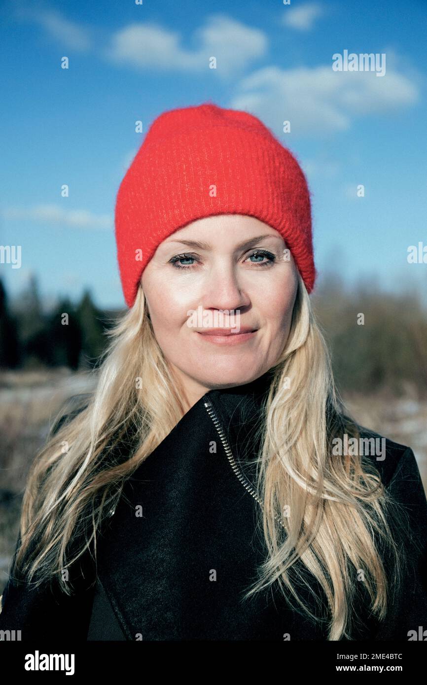 Femme mûre souriante portant un chapeau tricoté rouge Banque D'Images