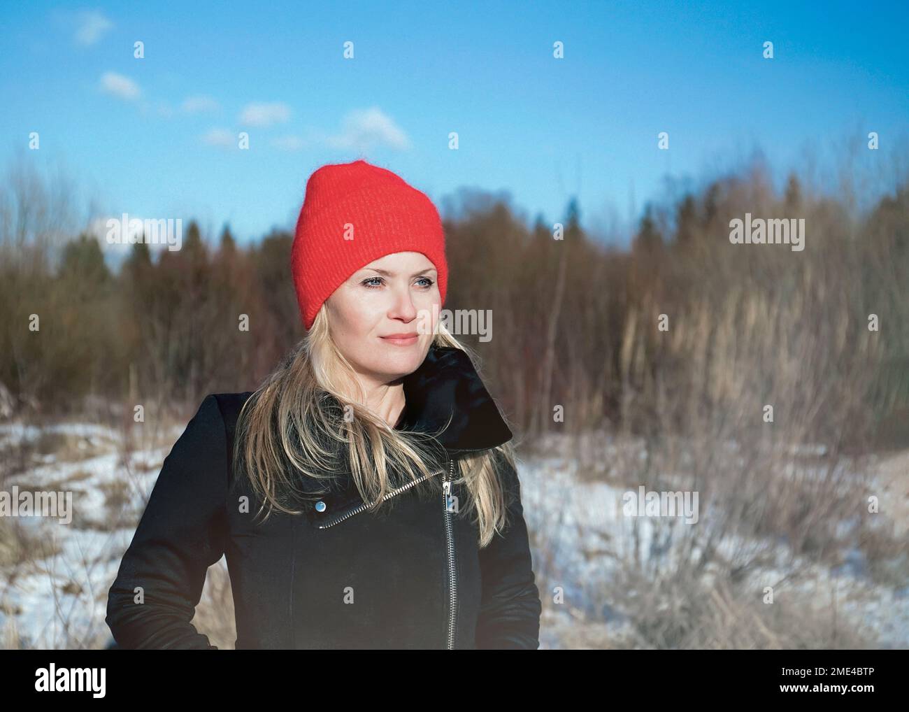 Femme réfléchie portant un chapeau tricoté rouge et regardant le paysage hivernal Banque D'Images