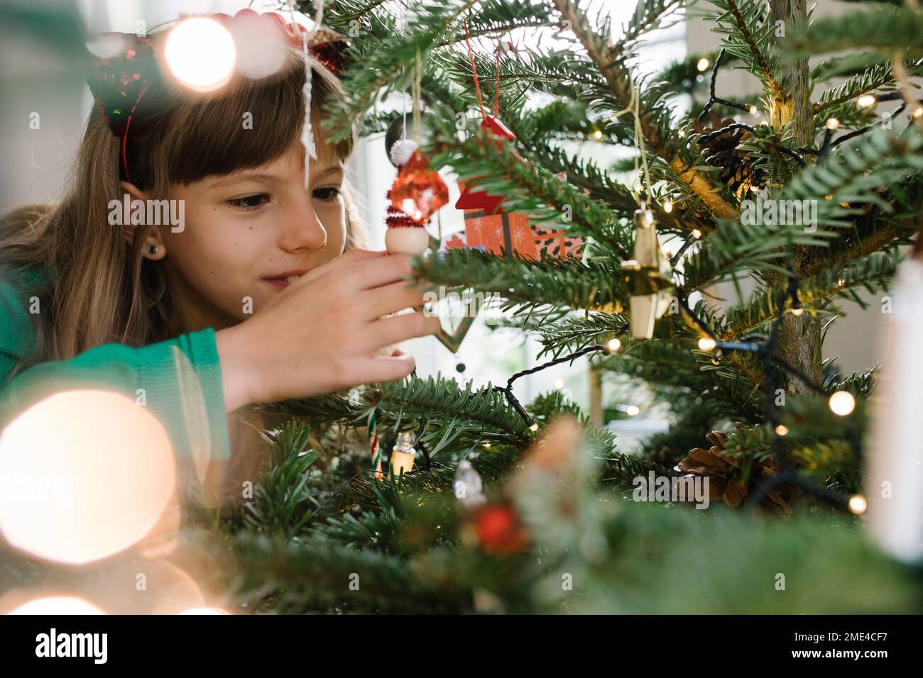 Girl decorating Christmas Tree at home Banque D'Images
