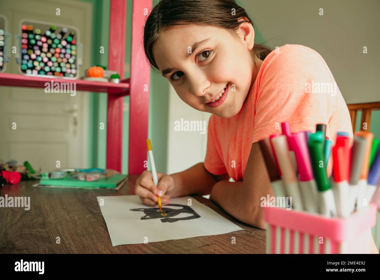 Sourire fille colorant photo de chat sur papier à la maison Banque D'Images