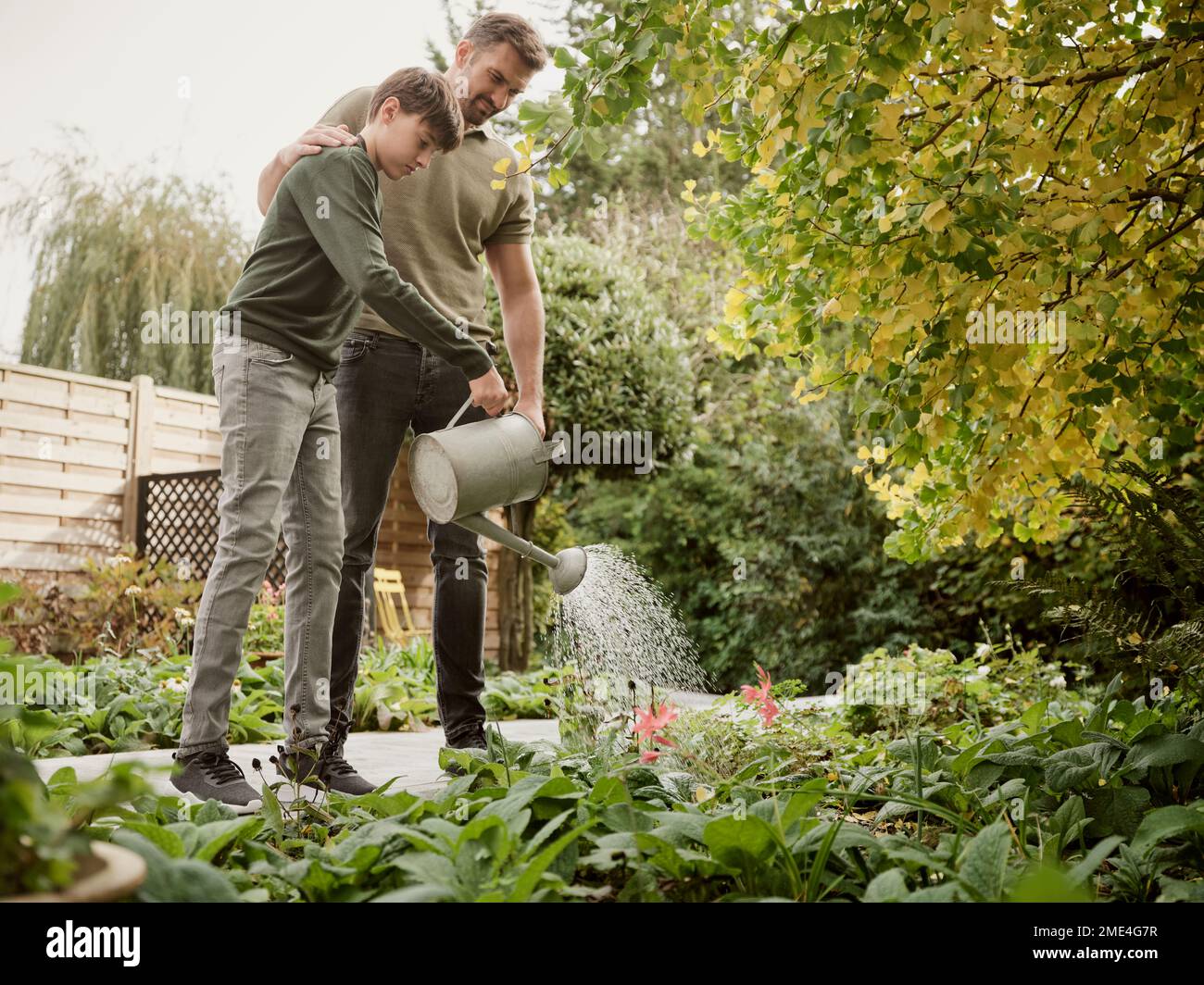 Père et fils debout dans les plantes d'arrosage de jardin Banque D'Images